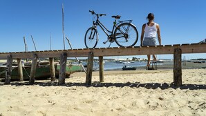 Eine Strandansicht mit einem Holzsteg, einem Fahrrad und einer Person, die auf dem Steg steht.