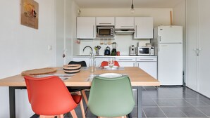 Eine moderne Küche mit weißen Schränken, einem Holztisch und zwei Stühlen.