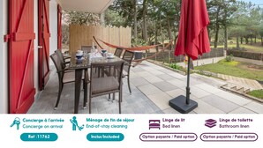 A patio with a table, chairs, a hammock, and a red umbrella.
