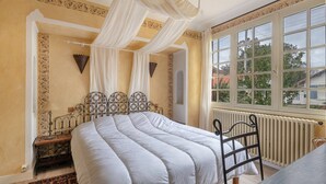 Une chambre avec un lit, une fenêtre donnant sur un beau paysage et un radiateur.