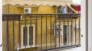 A balcony with a metal railing, a yellow awning, and air conditioning units. - Toledo Warm Renovated Studio (Naples)