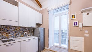 A modern kitchen with white cabinets, a stainless steel refrigerator, and a tiled backsplash. - Toledo Warm Renovated Studio (Naples)