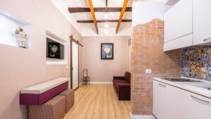 A compact kitchen with a brick accent wall, wooden beams, and a built-in bench. - Toledo Warm Renovated Studio (Naples)