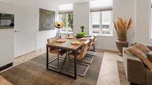 A modern dining area with a wooden table, chairs, and a large window providing natural light. - Fully equipped for business trips or cozy meals. (Roosendaal)