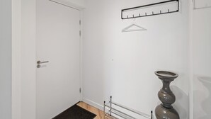 A hallway with a coat rack, a door, and a floor lamp. - Fully equipped for business trips or cozy meals. (Roosendaal)