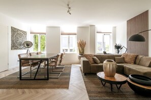 Een ruime woonkamer met een eethoek, grote ramen en een modern design.
