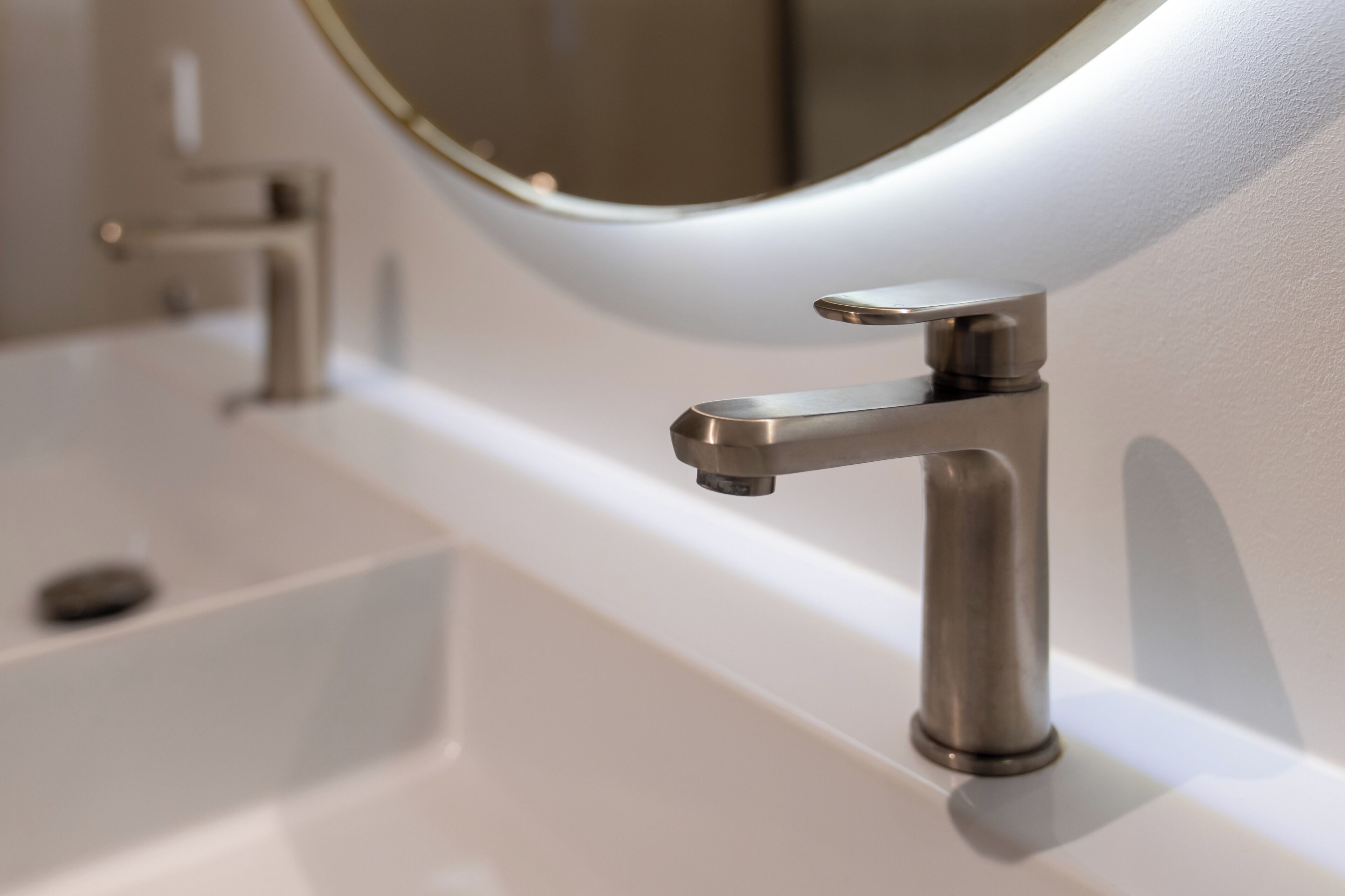A modern bathroom sink with a sleek faucet and a round mirror.