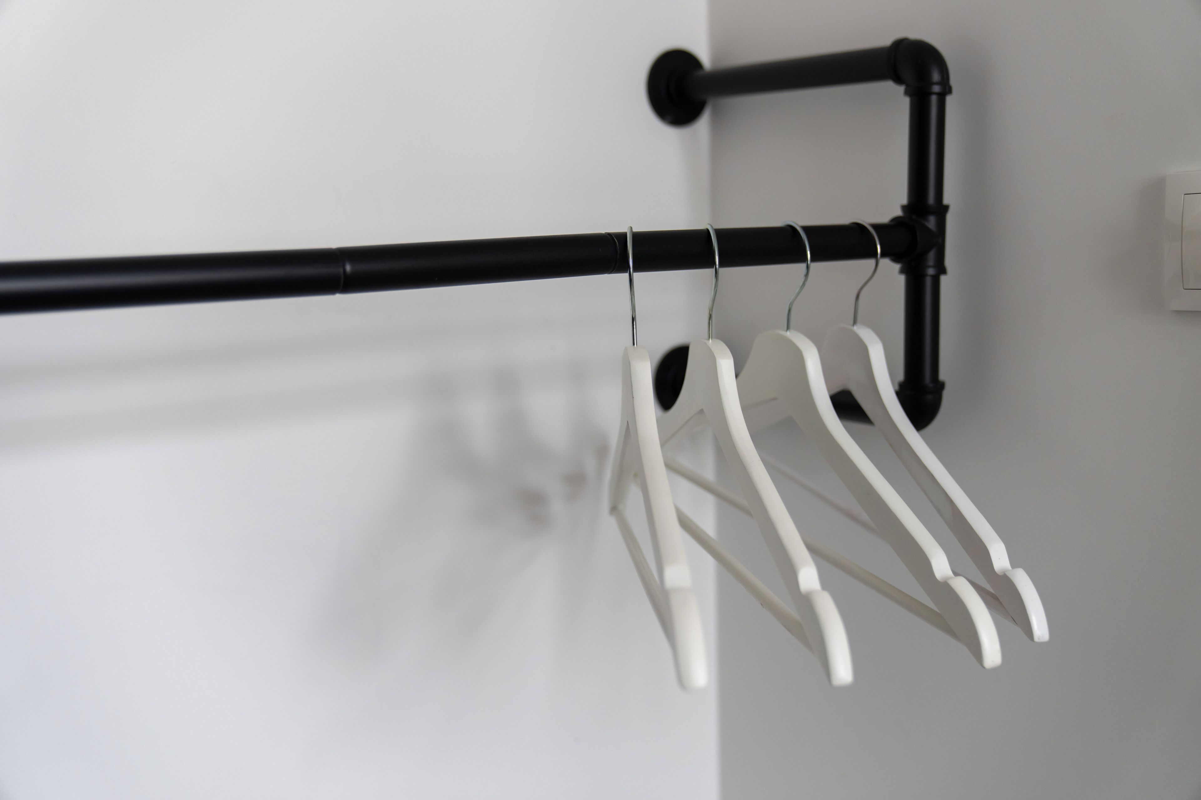 A black metal towel rack with white hanging towels against a white wall.