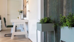 A modern interior with a white dining area, a wooden accent wall, and green plants in built-in planters.
