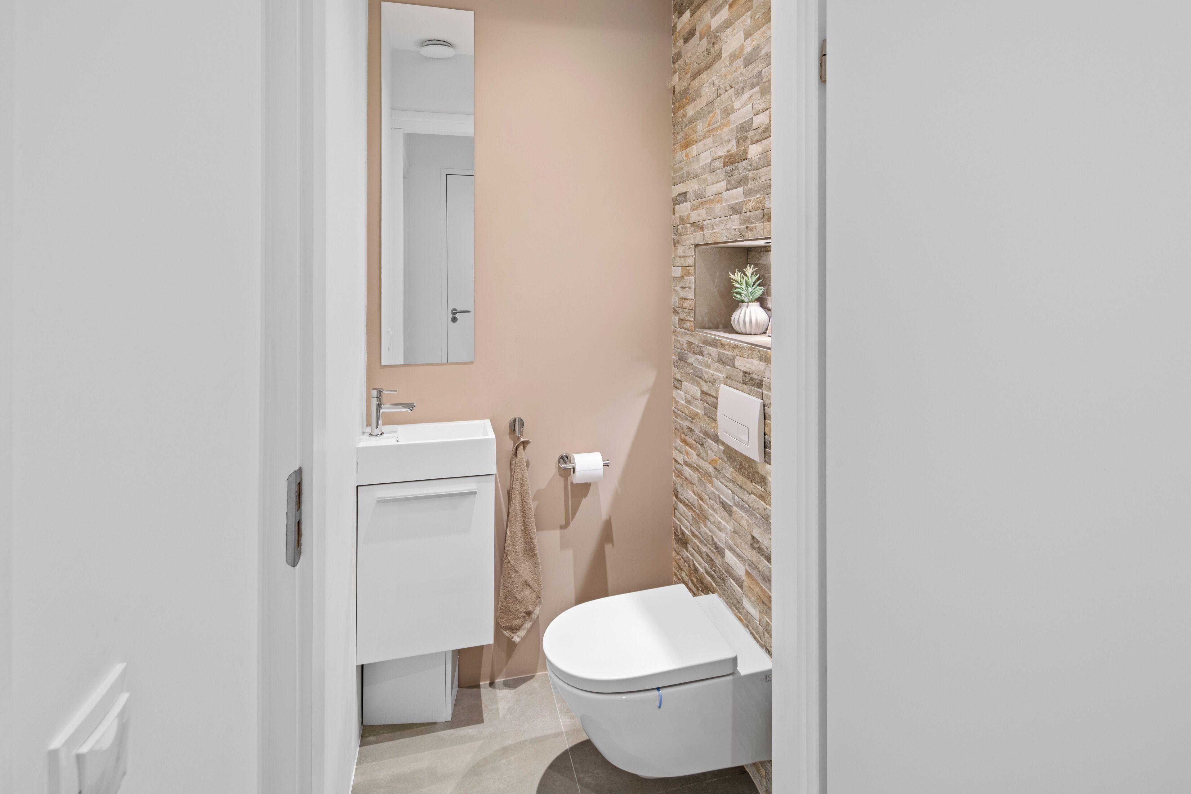 Een moderne badkamer met een wit toilet, een wastafel en een spiegel.