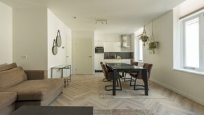 Un salon moderne avec un canapé, une table à manger et des chaises, et une cuisine en arrière-plan.