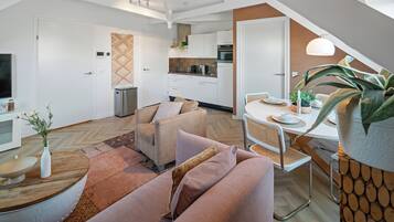 A modern living room with a sofa, a coffee table, and a dining area with a table and chairs.
