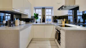 Une cuisine moderne avec des meubles blancs, un îlot central et une grande fenêtre.
