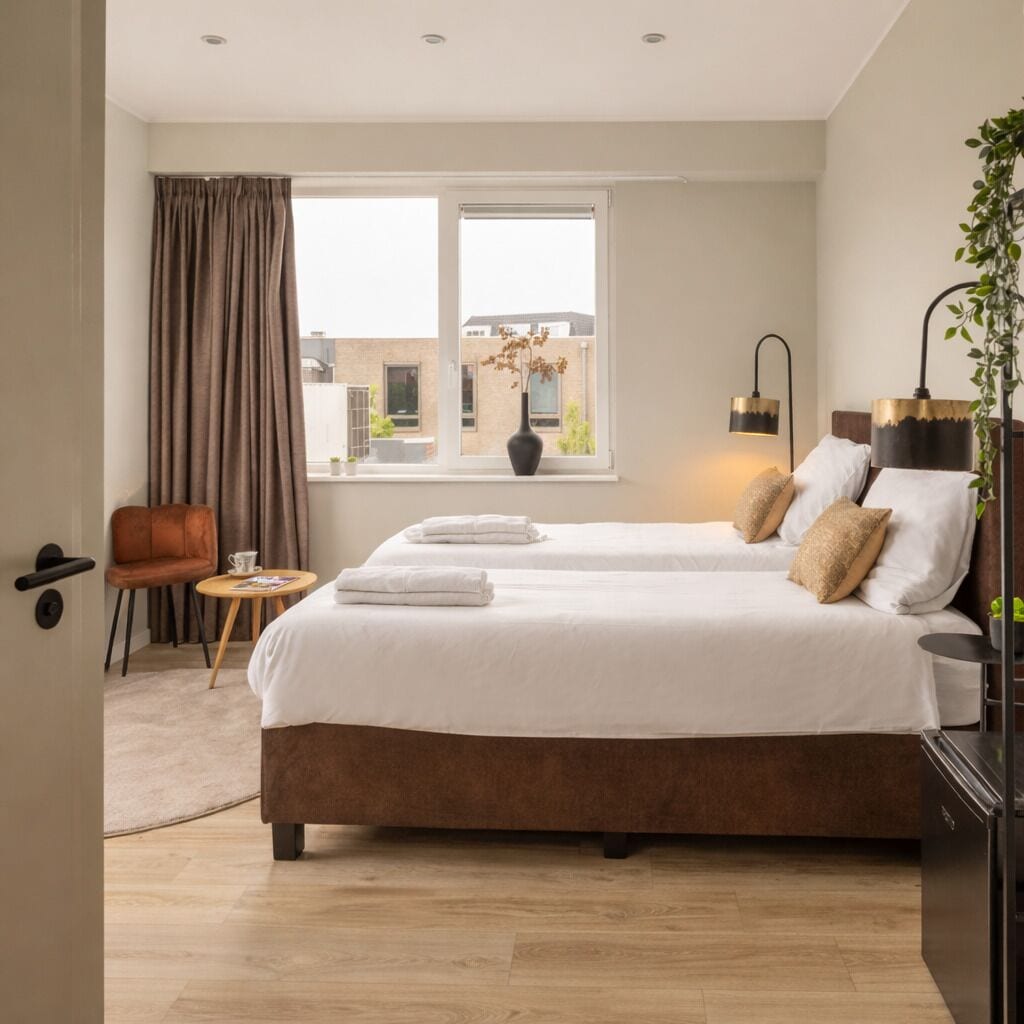 Cozy bedroom with box-spring bed, warm lighting and soft linens — perfect stay in Raamsdonksveer near shops and restaurants.