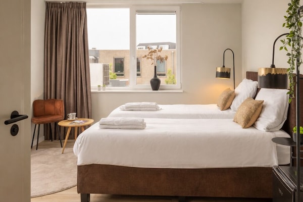 Cozy bedroom with box-spring bed, warm lighting and soft linens — perfect stay in Raamsdonksveer near shops and restaurants.