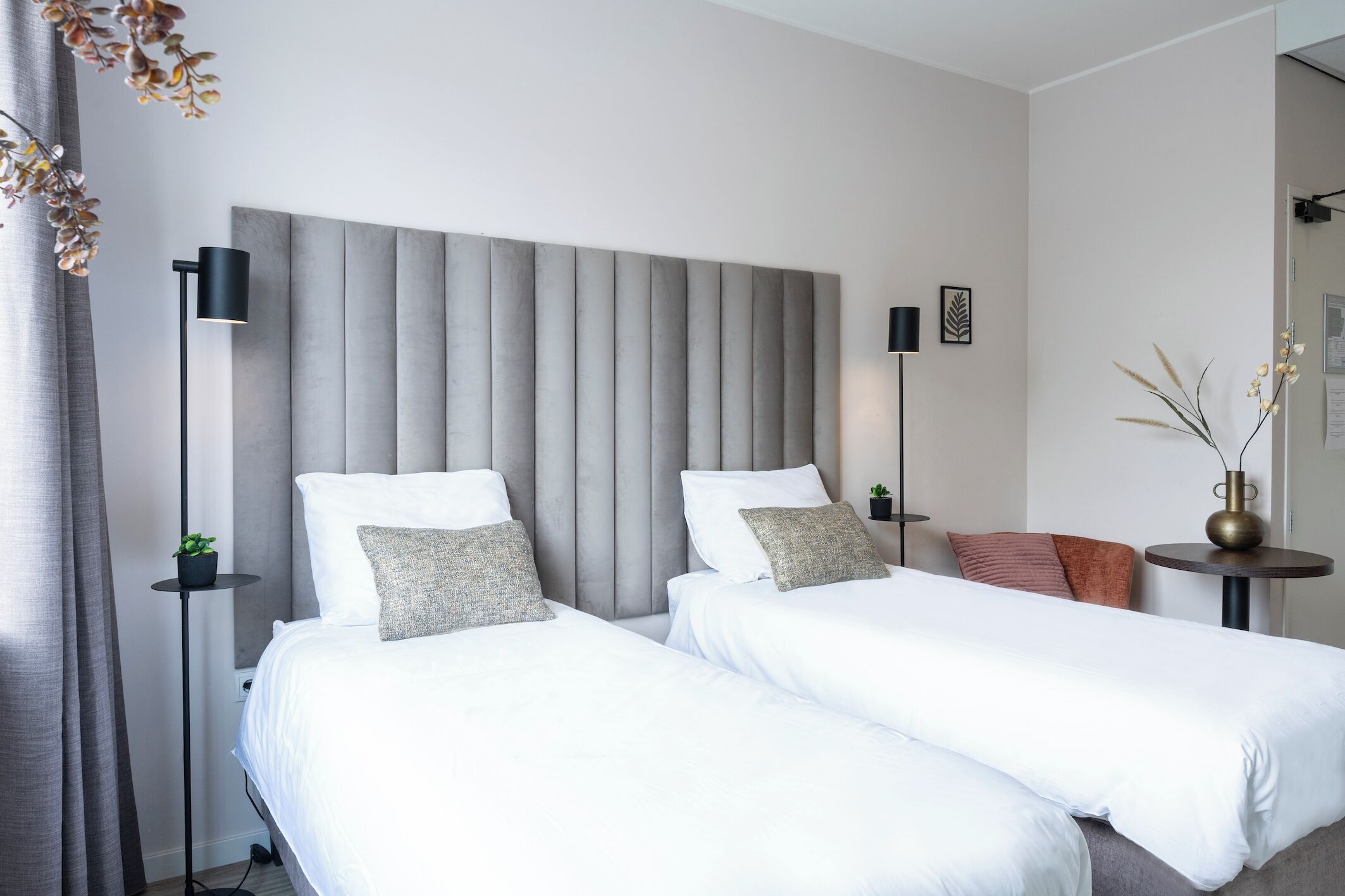 Comfortable twin beds with elegant headboards, complemented by soft lighting and a stylish seating area for relaxation.