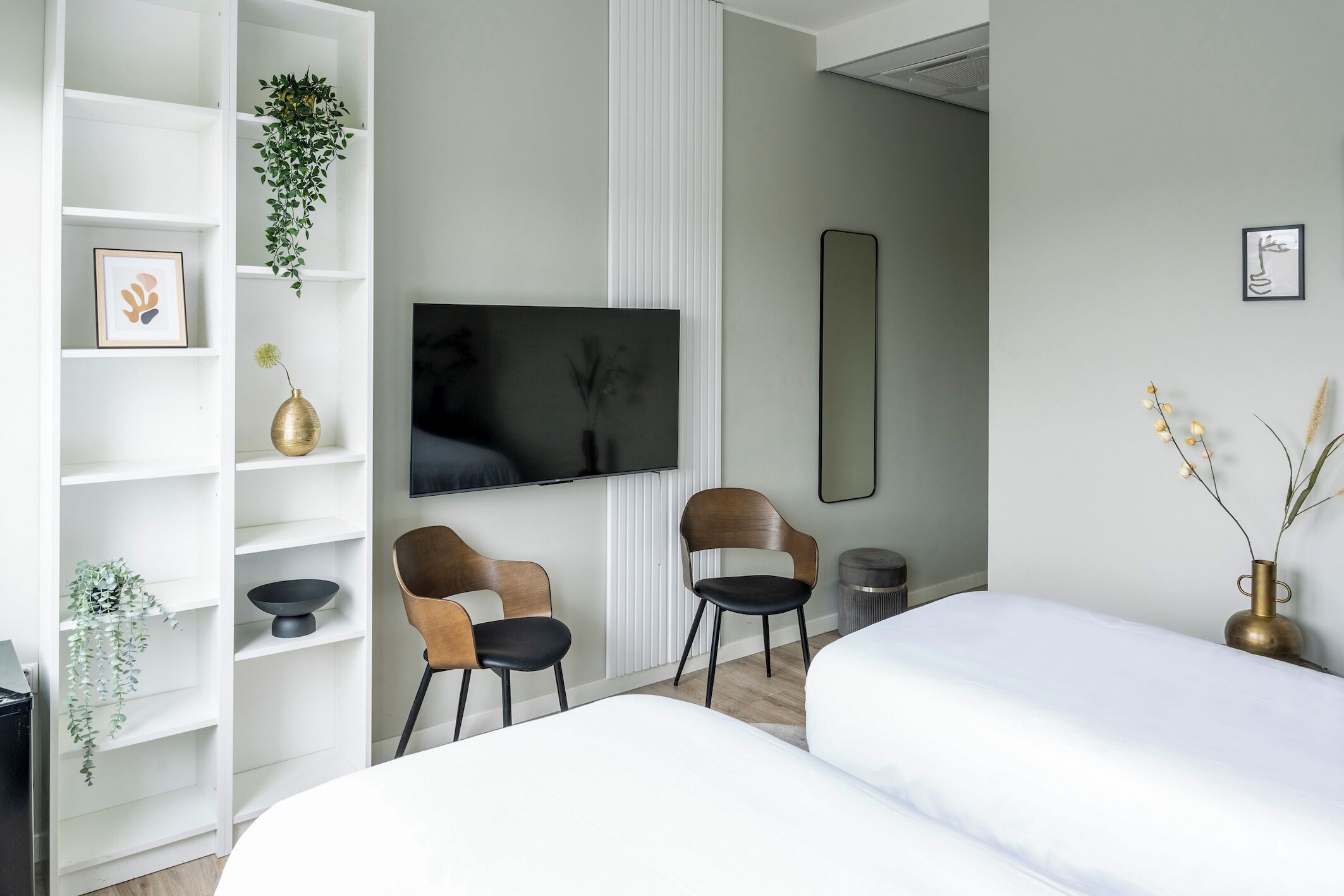 Stylish room featuring a flat-screen TV, modern shelving, and a comfortable seating area by the window.