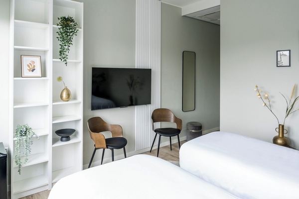 Stylish room featuring a flat-screen TV, modern shelving, and a comfortable seating area by the window.