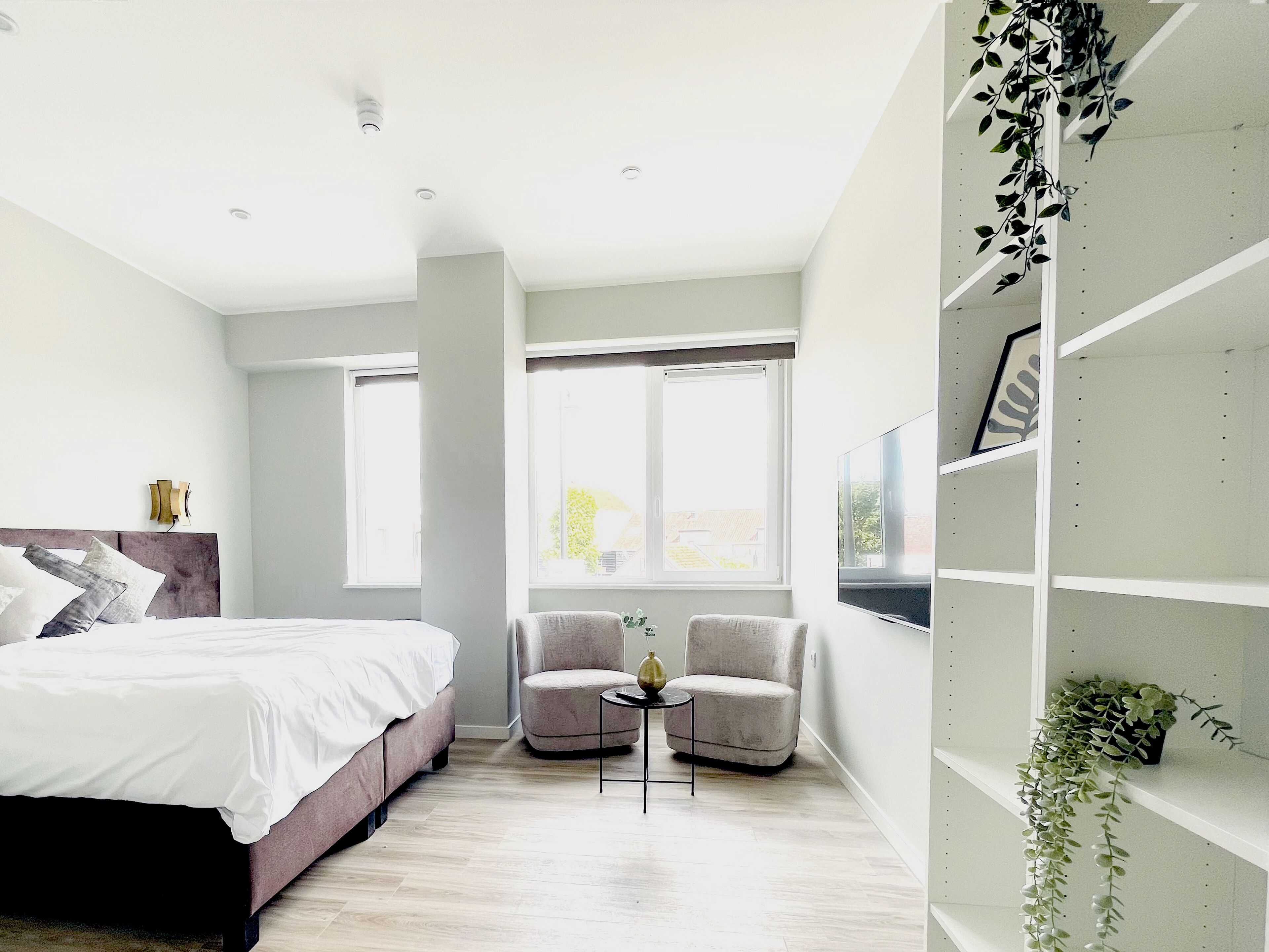 Bright bedroom with two comfy lounge chairs and natural light — a calm space to relax during your Raamsdonksveer stay.