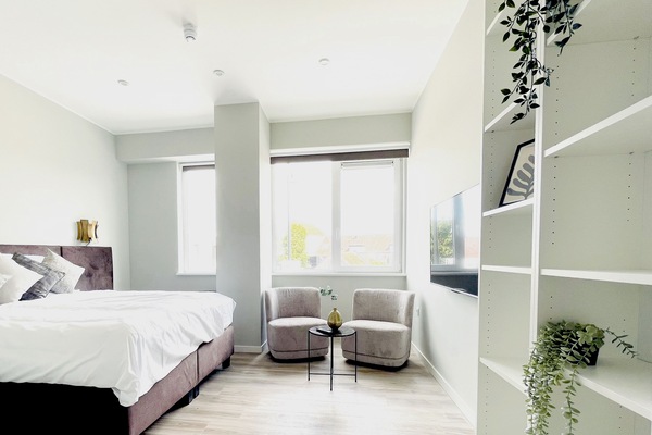 Bright bedroom with two comfy lounge chairs and natural light — a calm space to relax during your Raamsdonksveer stay.