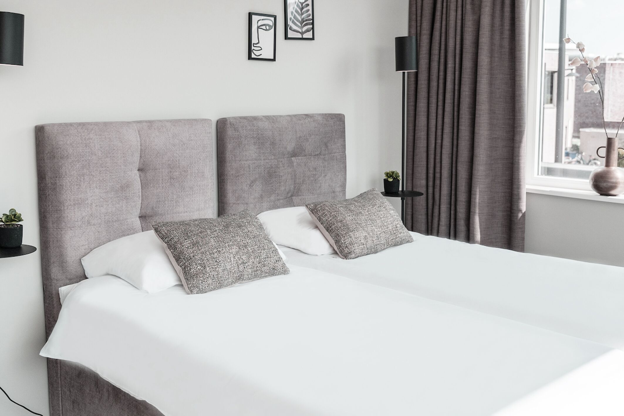 Lichte tweepersoonskamer met zachte bedlinnen, gezellige kussens en warm natuurlijk licht — een comfortabele ruimte om te ontspannen in Raamsdonksveer.