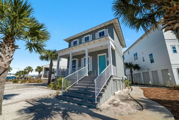 A two-story house with a front porch and a staircase leading to the entrance. - Cottages at Romar C1 - Gulf Side Cottage! (Orange Beach)