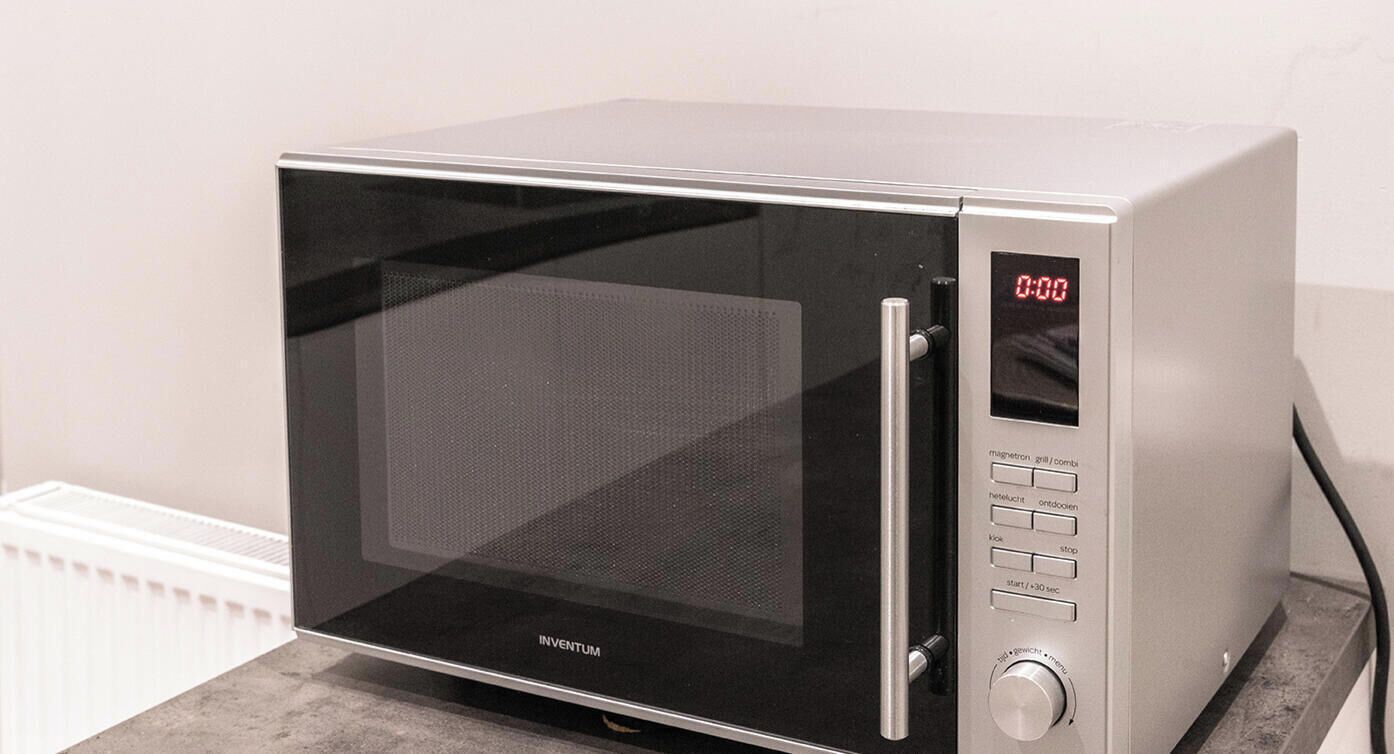 A microwave oven with a digital display, control buttons, and a stainless steel handle.