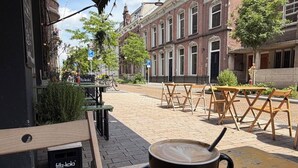 A café with outdoor seating, a coffee cup on a saucer, and a sign for 'fittz-kola'. - Cozy 35m² apartment with bath, fast WiFi, and charming herringbone floors. Perfect for a relaxing stay or business trip in the heart of Tilburg. (Tilburg)