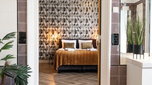 A bedroom with a patterned wallpaper, a bed with a striped blanket, and a wooden floor. - Cozy 35m² apartment with bath, fast WiFi, and charming herringbone floors. Perfect for a relaxing stay or business trip in the heart of Tilburg. (Tilburg)