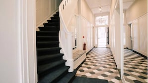 A hallway with a staircase, patterned floor, and white walls. - Cozy 35m² apartment with bath, fast WiFi, and charming herringbone floors. Perfect for a relaxing stay or business trip in the heart of Tilburg. (Tilburg)