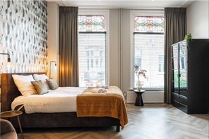A hotel room with a bed, a small table, a potted plant, and a cabinet. - Cozy 35m² apartment with bath, fast WiFi, and charming herringbone floors. Perfect for a relaxing stay or business trip in the heart of Tilburg. (Tilburg)