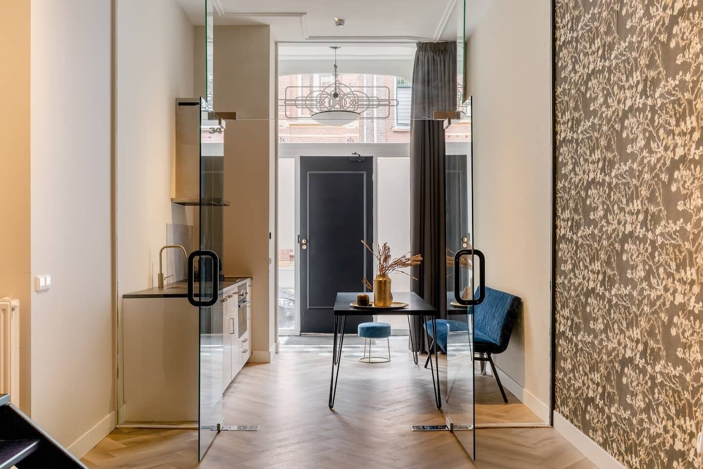 A sleek, modern living space with a dining area and a view through to the rest of the stylish apartment.