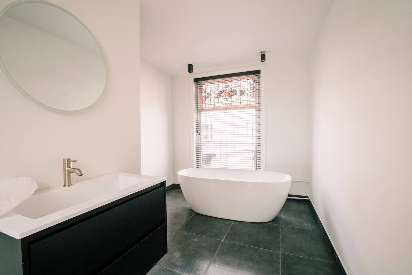 A modern bathroom with a freestanding bathtub, a large mirror, and a black vanity.