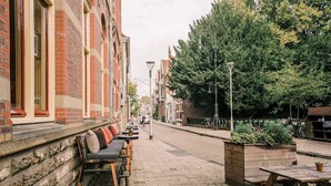 Un edificio de ladrillo con una fila de mesas al aire libre y una mesa de madera.
