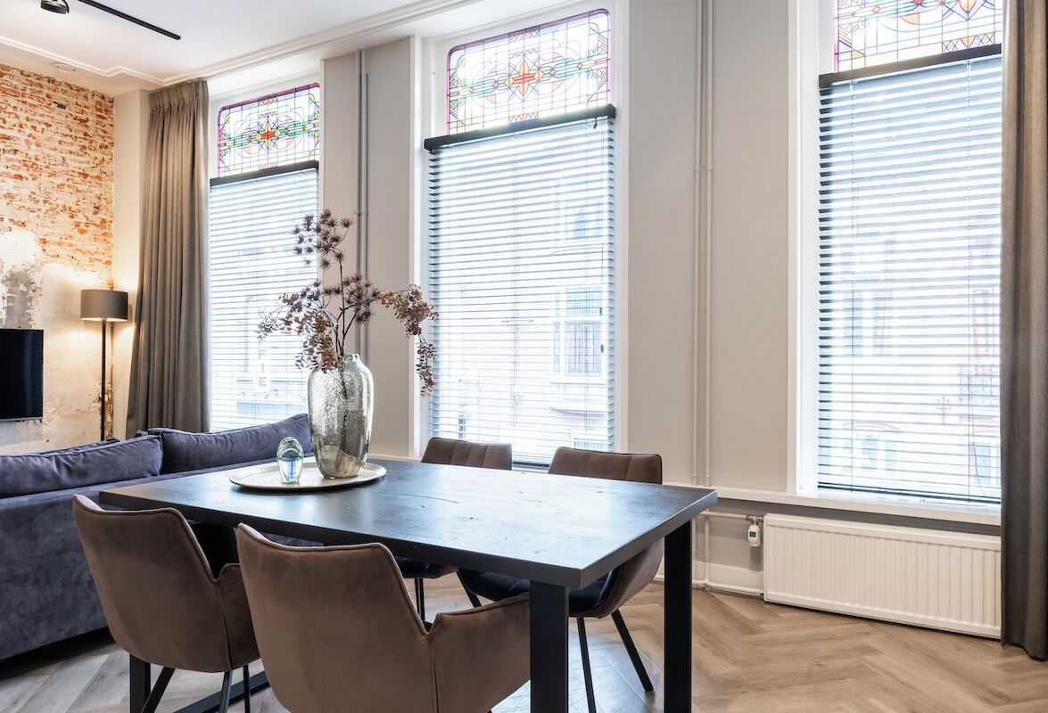 A dining area with a dark wooden table, six chairs, and a vase with dried flowers.