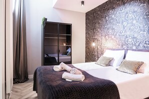 A modern bedroom with a large bed, a wardrobe, and a patterned wall.