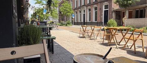 A café with outdoor seating, a coffee cup on a saucer, and a sign for 'fittz-kola'.