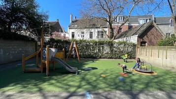 Une aire de jeux avec un toboggan, des balançoires et une structure d’escalade.
