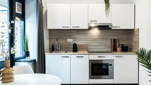 Una cocina moderna con armarios blancos, horno integrado y cafetera.
