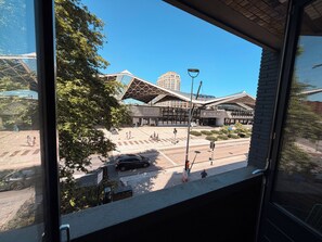 Ein modernes Gebäude mit außergewöhnlichem architektonischen Design, einem wolkenlosen Himmel und einer Straße mit Fußgängern und Fahrzeugen.