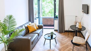 Una sala de estar moderna con un sofá de cuero, una mesa redonda y un comedor con una mesa pequeña y sillas.