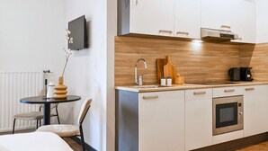 Una habitación de hotel compacta con kitchenette, un pequeño comedor y una cama.
