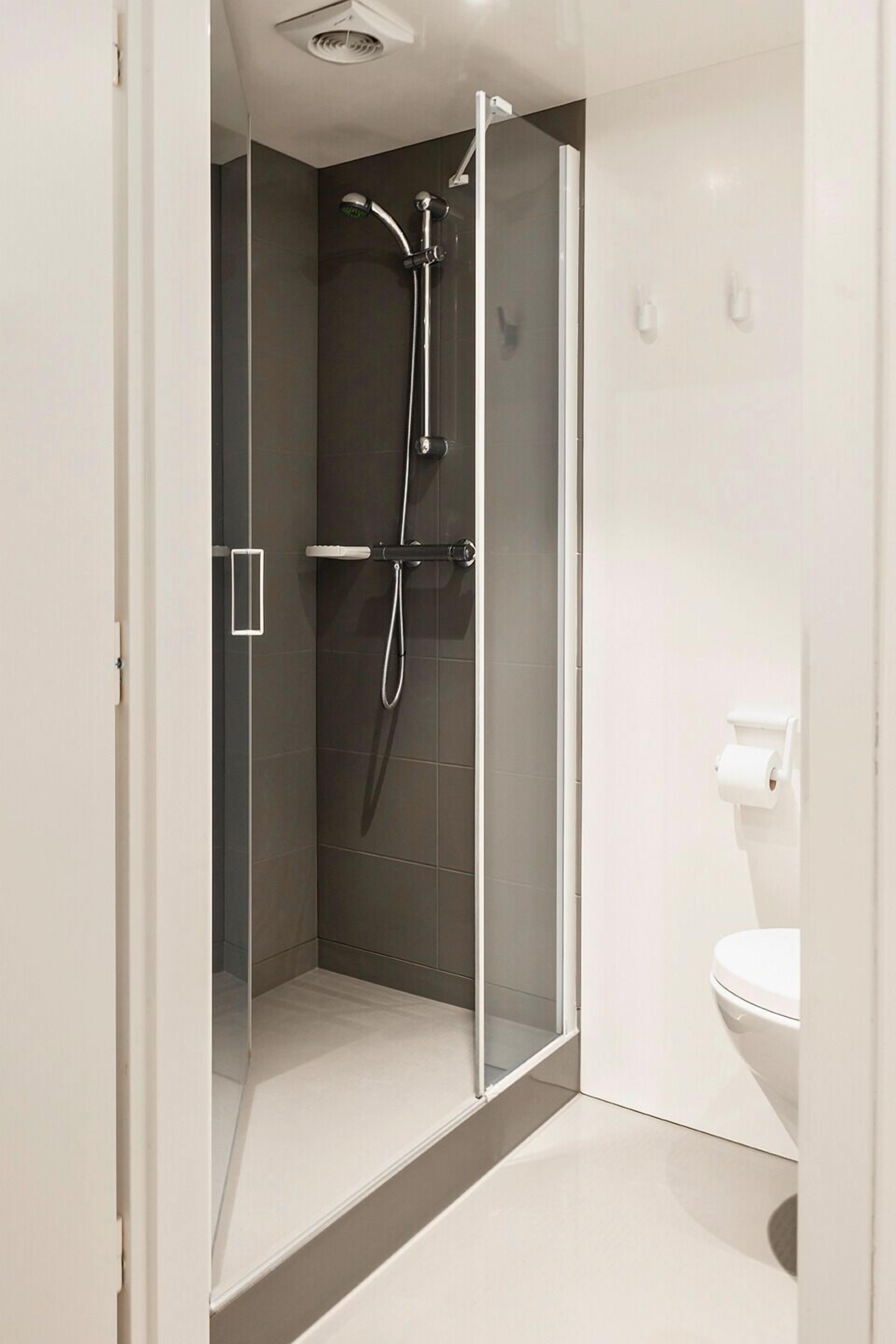 Un baño moderno con ducha de vidrio, inodoro y lavamanos blanco.