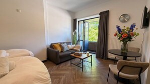 Una habitación de hotel moderna con cama, sofá, mesa de centro y una pequeña mesa de comedor.