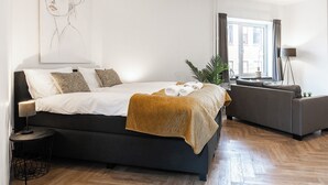 A modern bedroom with a bed, a sofa, a floor lamp, and a large window. - Modern space studio apartments near Hotel Central, ideal for lovers of refinement. (Tilburg)