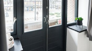 A modern room with a large window, a black door, and a small plant on a shelf. - Modern space studio apartments near Hotel Central, ideal for lovers of refinement. (Tilburg)