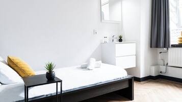 A modern bedroom with a bed, bedside table, and a small potted plant.
