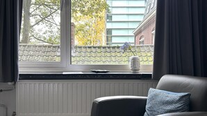 A room with a window, a radiator, a chair, and a view of buildings and trees outside. - Unwind in a contemporary, newly renovated single room, conveniently located in central Tilburg (Tilburg)