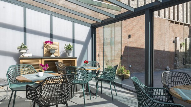 Un patio al aire libre con sillas de mimbre, una mesa de madera y plantas en macetas.