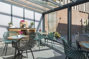 Une terrasse extérieure avec des chaises en osier, une table en bois et des plantes en pot.